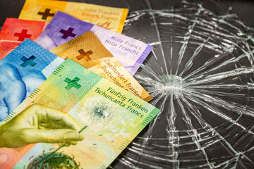 Swiss francs lying on broken glass, financial concept, Weakening of the Swiss currency