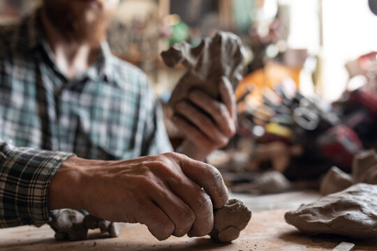 man tears off pieces of clay