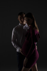 portrait of a pregnant couple on a black background, pregnant couple close up