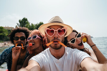 Young people at the beach taking a funny selfie eating