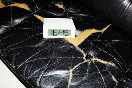 Broken leather sofa with a digital clock with hard direct flashlight