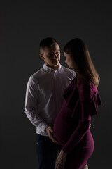portrait of a couple, pregnant couple on a black background close up, fashion pregnant model, pregnant woman stands on a black background, studio pregnancy photo shoot