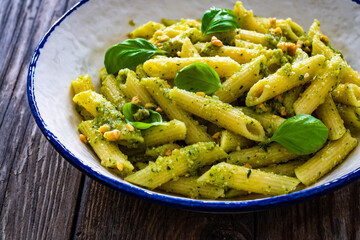 Penne with basil pesto sauce on wooden table
