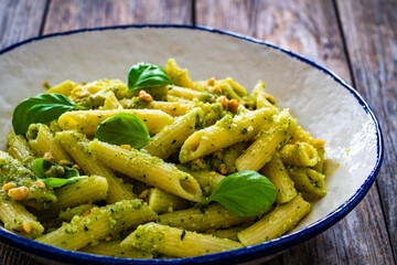 Penne with basil pesto sauce on wooden table
