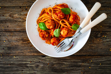 Spaghetti meatballs in tomato sauce on wooden table 