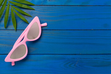 Stylish pink sunglasses on wooden background, top view. Summer concept