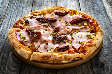 Pizza mortadella with mozzarella cheese and sun dried tomatoes on wooden table
