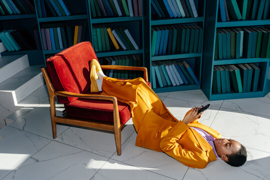 Woman lying on floor and checking messages on smartphone