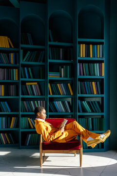 Relaxed woman sitting in armchair and reading book 