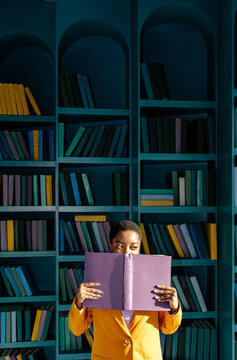 Woman peering out from behind opened book 