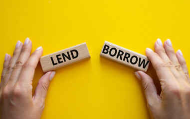 Lend or Borrow symbol. Concept word Lend or Borrow on wooden blocks. Businessman hand. Beautiful yellow background. Business and Lend or Borrow concept. Copy space
