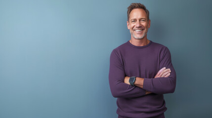 A smiling man with crossed arms in a purple sweater stands before a blue background.