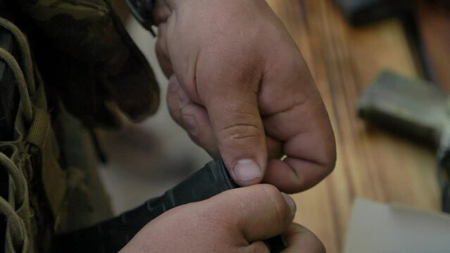 Ukrainian soldier loading ammo in magazine close-up on hands