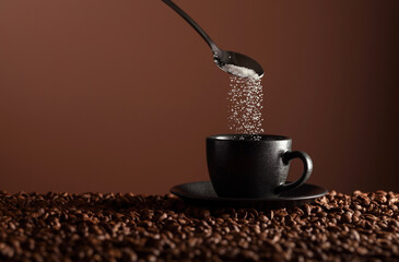 Sugar is poured into a cup of coffee.