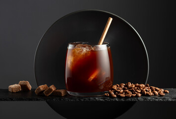 Black coffee with ice on a black background.