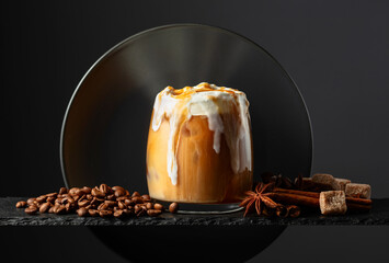 Iced coffee with whipped cream and caramel sauce on a black background.