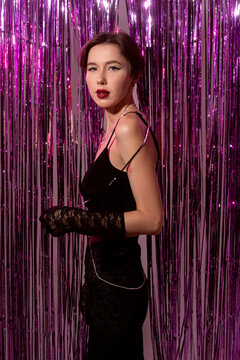 Woman standing against shiny curtain