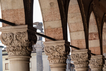Columns of Loggia del Lionello with scenic view of Venetian style clock tower Torre dell'Orologio...