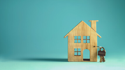 Obraz na płótnie Canvas A wooden house figurine with a key next to it, symbolizing homeownership, new rental, or visualizing the concept of moving into a new home. Minimalism. Blue background and studio photography.