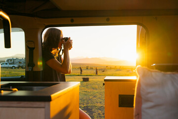 Photographer by her camper van taking a photo at sunset 