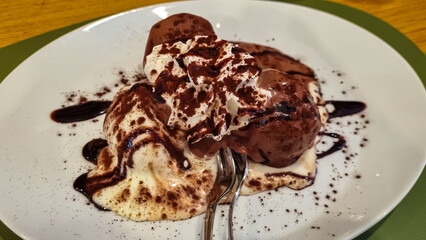 Chocolate Profiterole. Sweet dessert on white plate. Homemade profiteroles with cream and chocolate sauce served in a bar in the historic city center of Tarvisio, Friuli Venezia Giulia, Italy, Europe