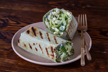 Homemade burrito wraps with green cabbage, cucumber, herbs and sour cream for healthy breakfast on plate, closeup - 777679346