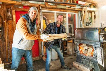 sugar shack, two maple farmers wearing a traditional clothe working doing sugar sirop and puting some wood on fire
