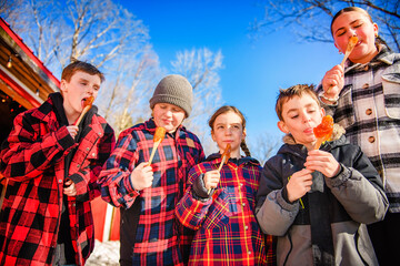 Photo showing children tasting maple syrup with wooden spoon - 777682747