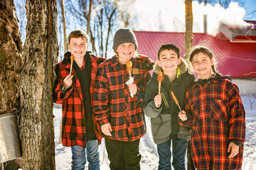 Photo showing children tasting maple syrup with wooden spoon - 777683159