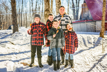 Photo showing children tasting maple syrup with wooden spoon