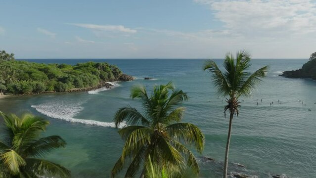 Aerial Drone reveal shot of Hiriketiya Beach, Sri Lanka, with surfers and crashing waves on the Indian Ocean &nbsp;