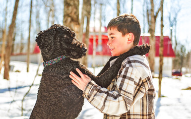 Cute boy playing with happy Goldendoodle on spring season