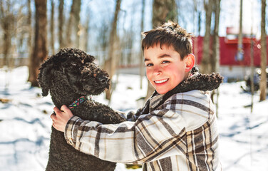 Cute boy playing with happy Goldendoodle on spring season