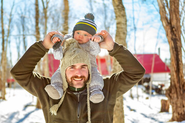 father and baby close to a maple shack having fun together