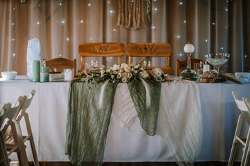 Valmiera, Latvia - Augist 13, 2023 - Elegantly set wedding table with a floral centerpiece, green...