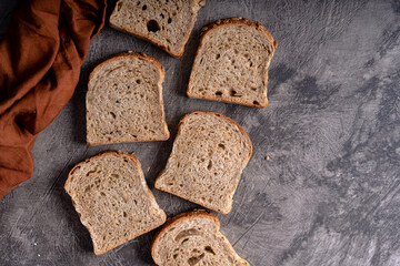 Sliced whole grain loaf bread on dark rustic wooden background