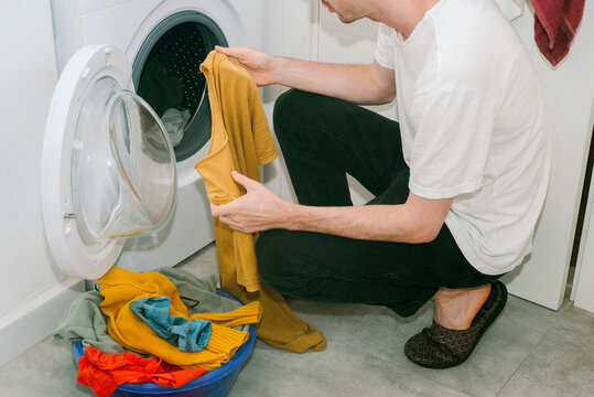 A young man sorting clothes before washing them 