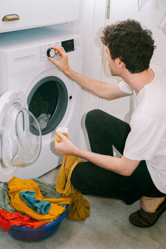 A man sets the washing machine mode