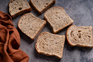 Sliced whole grain loaf bread on dark rustic wooden background