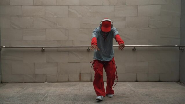 Handsome choreographer practice street dance in gray background. Young attractive b boy dancer perform while wearing stylish cloth. Feeling of lively step. Copy space. Outdoor sport 2024. Sprightly.