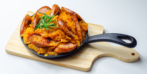 Traditional Polish dish called bigos made of sauerkraut, sausage and mushrooms, food served warm in a cast iron pan - 777690566