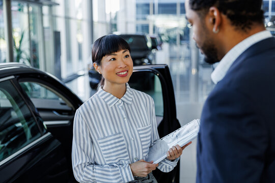 Asian executive discussing with male customer at dealership