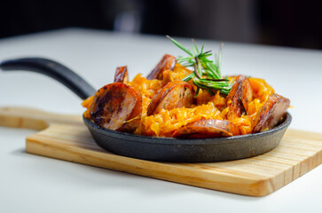 Traditional Polish dish called bigos made of sauerkraut, sausage and mushrooms, food served warm in a cast iron pan - 777690741