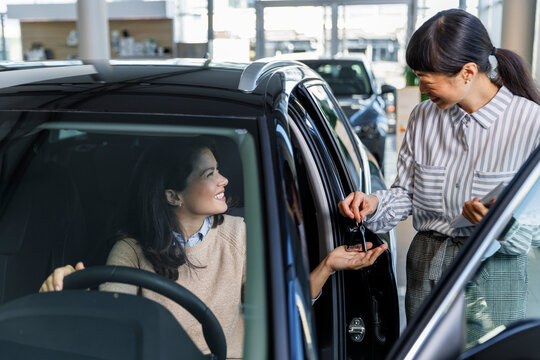 Female executive giving keys to happy new car owner 