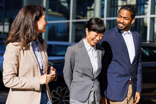 Smiling sales manager discussing with colleagues in car dealership