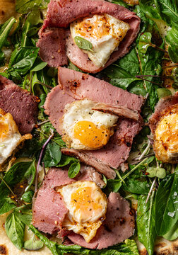 Pastrami pizza with quail eggs and fresh arugula