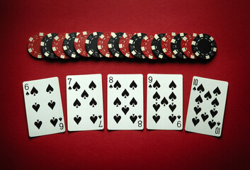 Playing cards and chips on a red table in a poker club. Concept of a successful straight flush...