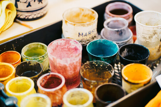 Jars with different paint colors placed on tray in workshop