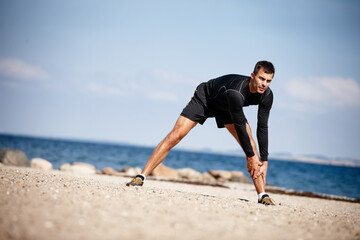 Man, stretching and sports at beach for exercise with fitness motivation, sand and blue sky. Male...