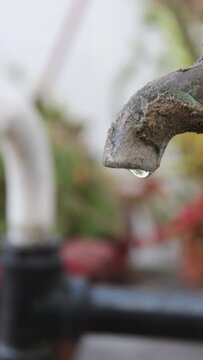 Escases de agua por el camb&iacute;o clim&aacute;tico. El grifo gotea por la escases de agua por la sequia. El grifo viejo abierto desprende gotas transparentes de l&iacute;quido para beber con fondo difuminado.